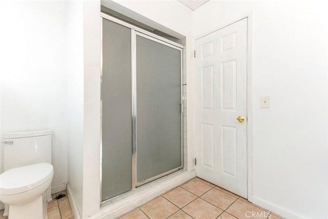 full bathroom featuring tile patterned flooring, toilet, and a stall shower