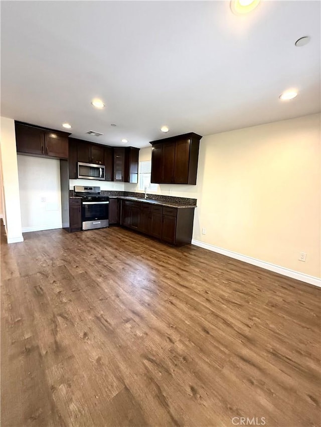 645 E 78th St, Los Angeles, CA 90001 - kitchen featuring stainless steel appliances, dark countertops, dark brown cabinets, wood finished floors, and recessed lighting