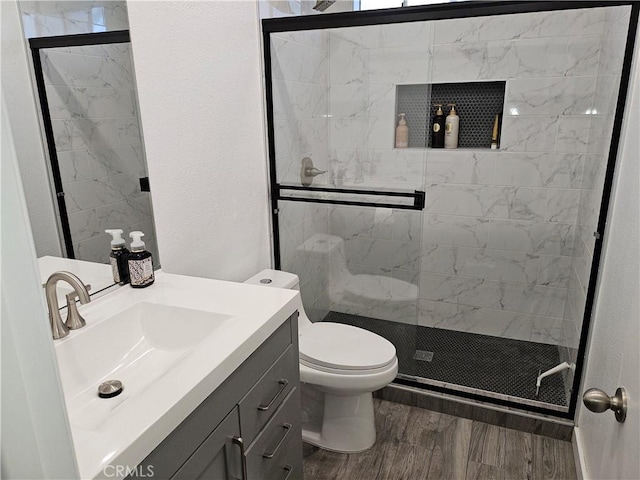 full bathroom with toilet, wood finished floors, a shower stall, vanity, and a textured wall