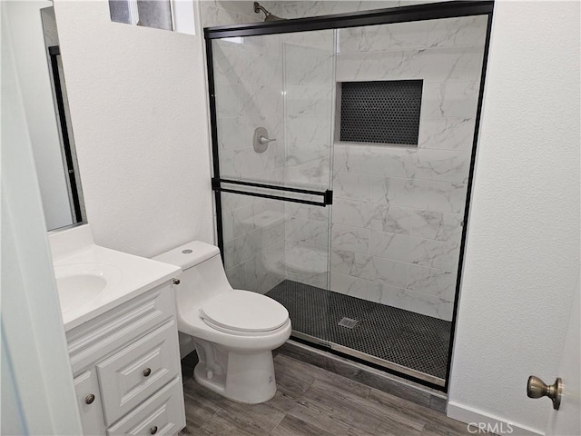 full bath with vanity, wood finished floors, a shower stall, toilet, and a textured wall