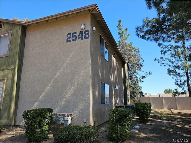 view of side of property featuring stucco siding and fence