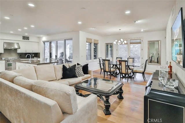 living area with baseboards, light wood-style flooring, visible vents, and recessed lighting