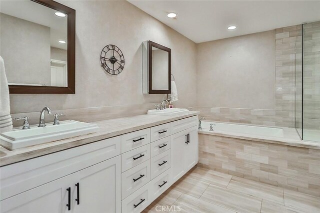 full bath featuring a garden tub, a sink, double vanity, and recessed lighting