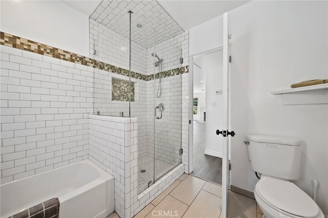full bathroom featuring baseboards, toilet, tile patterned floors, a washtub, and a stall shower