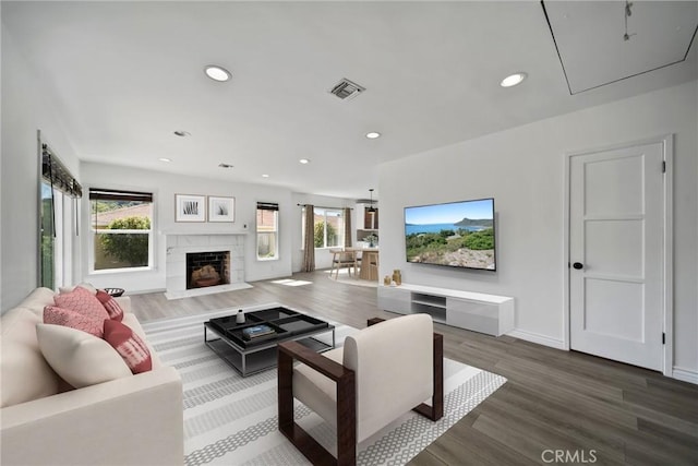 living area featuring recessed lighting, attic access, a fireplace with flush hearth, visible vents, and wood finished floors