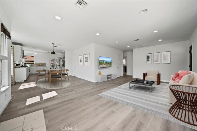 living room featuring recessed lighting, visible vents, baseboards, and light wood-style flooring