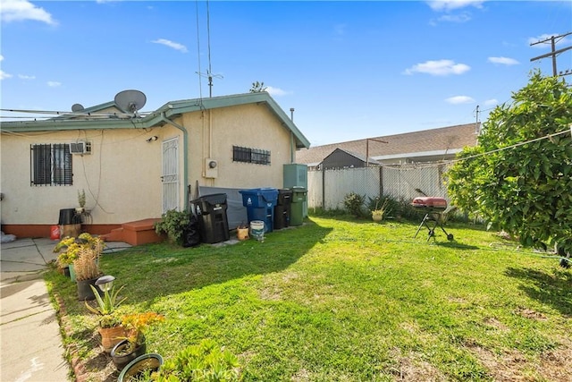 back of property featuring stucco siding, a yard, and fence