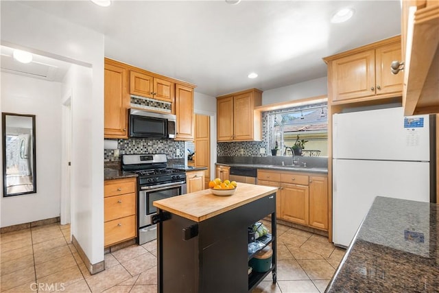 kitchen with butcher block countertops, stainless steel appliances, decorative backsplash, and a sink