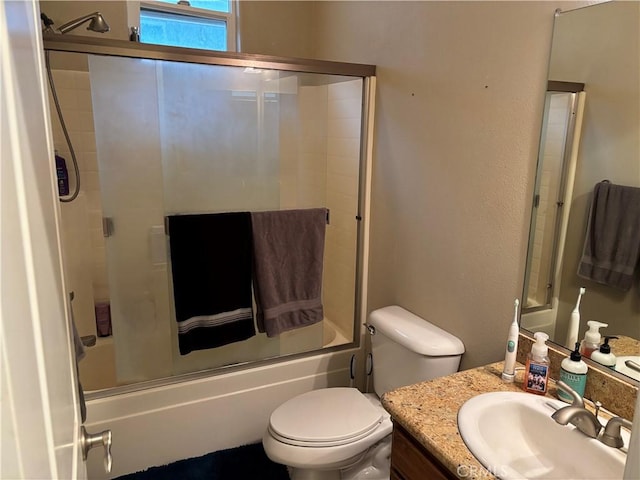 bathroom featuring combined bath / shower with glass door, toilet, and vanity