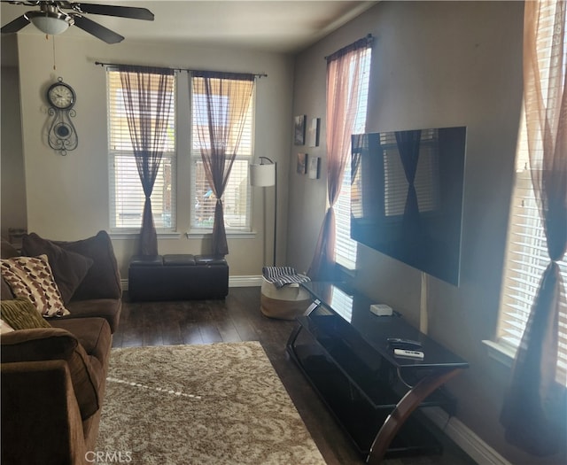 living area featuring a wealth of natural light, wood finished floors, baseboards, and a ceiling fan