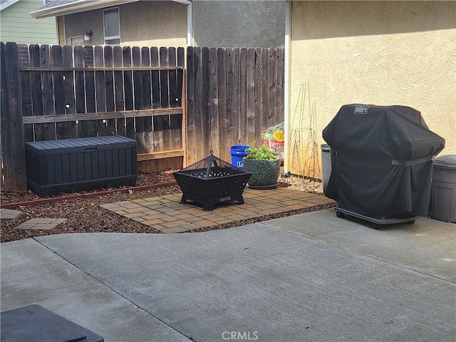 view of patio featuring grilling area, a fire pit, and fence