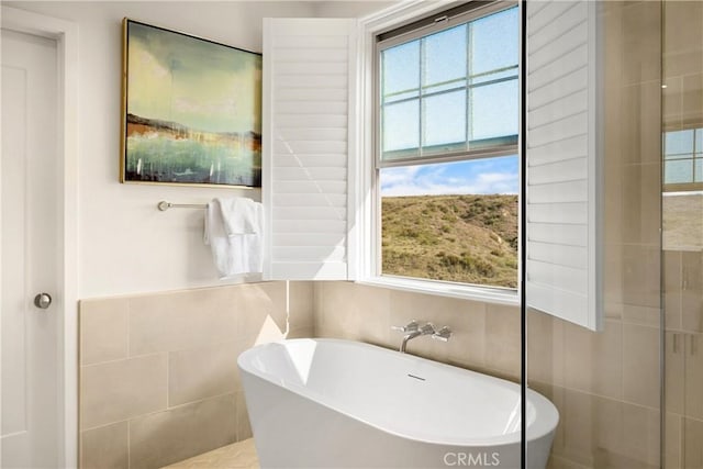 full bathroom featuring tile walls and a freestanding tub