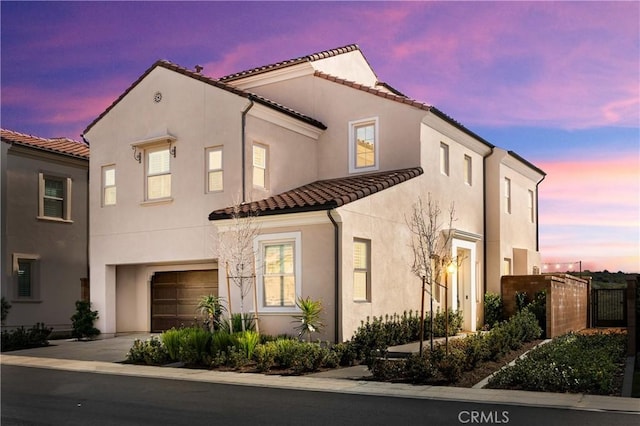 mediterranean / spanish-style house with stucco siding, concrete driveway, an attached garage, and a tiled roof