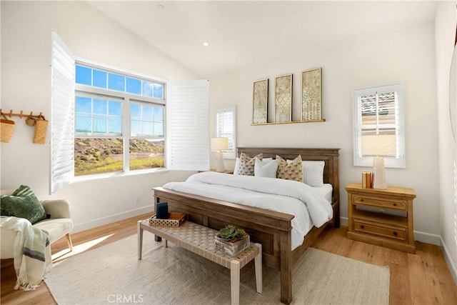 bedroom with light wood-type flooring, baseboards, and vaulted ceiling