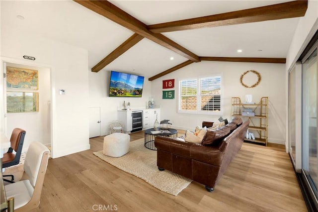 living room featuring light wood finished floors, vaulted ceiling with beams, baseboards, beverage cooler, and bar