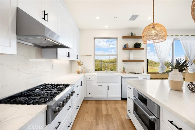 kitchen featuring a sink, under cabinet range hood, gas stovetop, white cabinets, and dishwasher