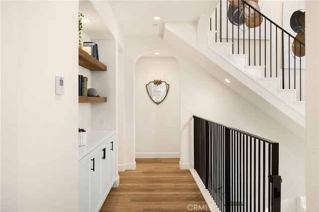 hall with stairs, light wood-style flooring, recessed lighting, and baseboards