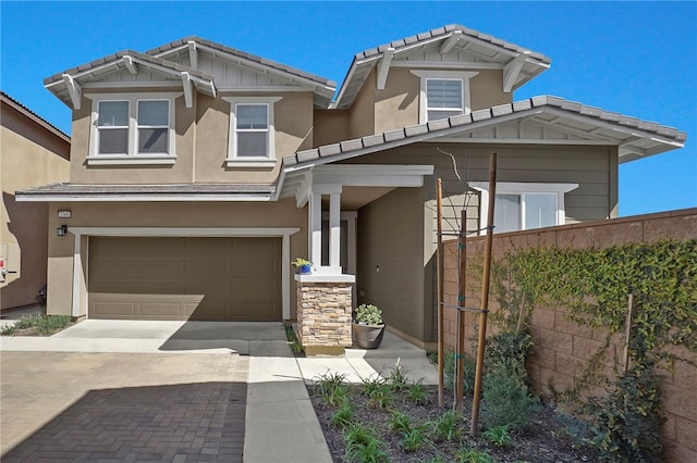 craftsman-style house with a tiled roof, an attached garage, driveway, and stucco siding