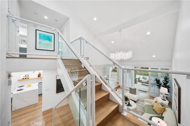 stairs with an inviting chandelier, beamed ceiling, recessed lighting, and wood finished floors