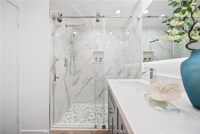 full bathroom featuring a marble finish shower and vanity