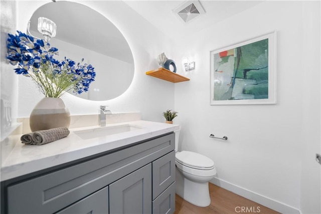 bathroom featuring vanity, wood finished floors, visible vents, baseboards, and toilet