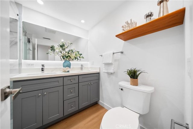 bathroom featuring a sink, toilet, wood finished floors, and double vanity