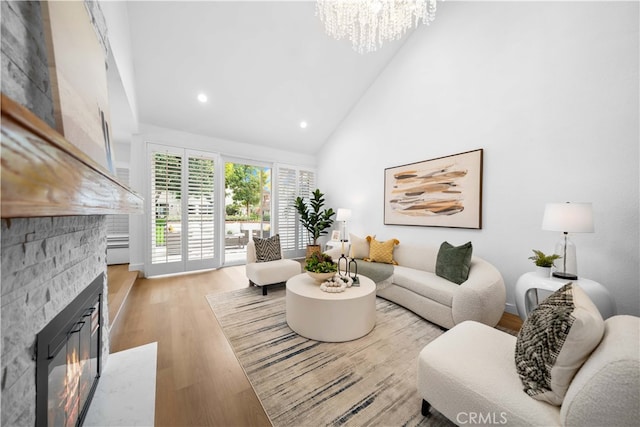 living room featuring light wood finished floors, high vaulted ceiling, an inviting chandelier, recessed lighting, and a stone fireplace