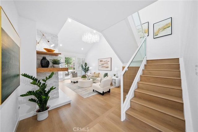 living room with a multi sided fireplace, stairs, an inviting chandelier, and wood finished floors