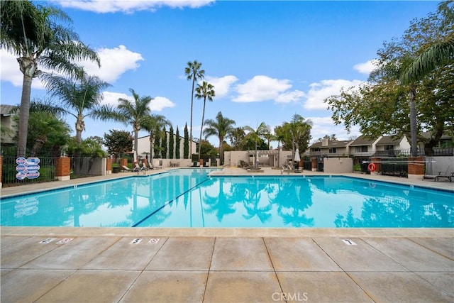 pool with a patio area and fence
