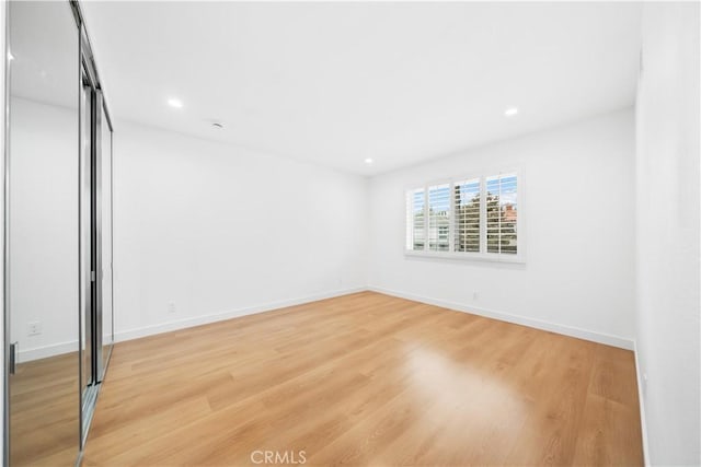 unfurnished bedroom featuring a closet, recessed lighting, light wood-type flooring, and baseboards