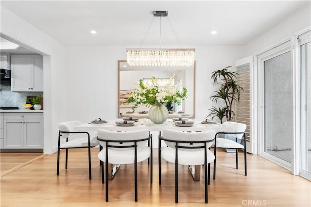 dining room featuring light wood-type flooring, a healthy amount of sunlight, and a chandelier
