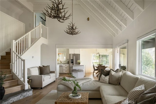 living area with a chandelier, stairway, beamed ceiling, and wood finished floors