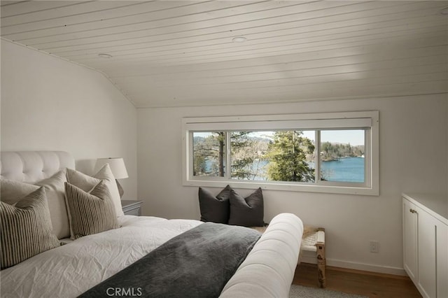 bedroom featuring wood finished floors, baseboards, multiple windows, and lofted ceiling