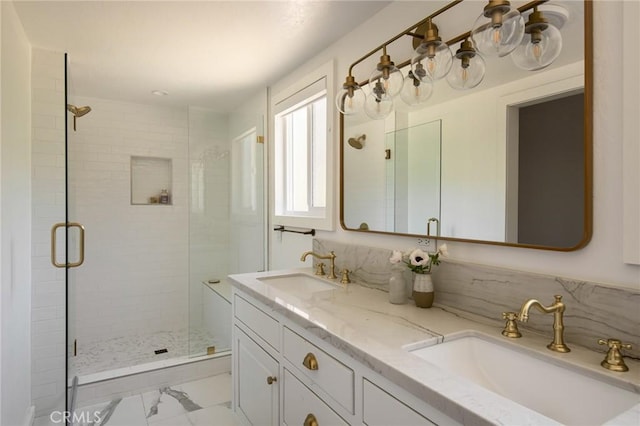 full bath with double vanity, marble finish floor, a sink, and a stall shower