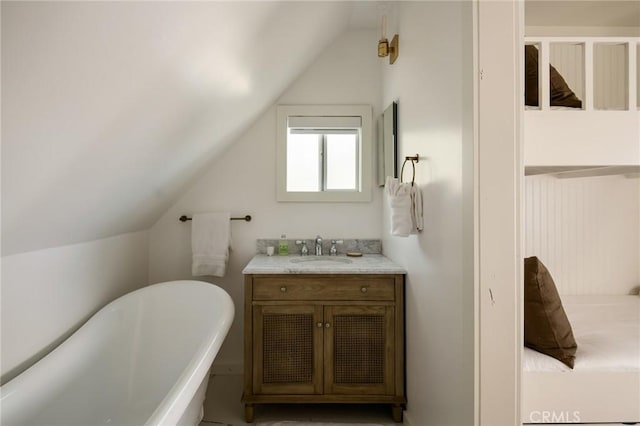 bathroom with a freestanding tub, vanity, and vaulted ceiling