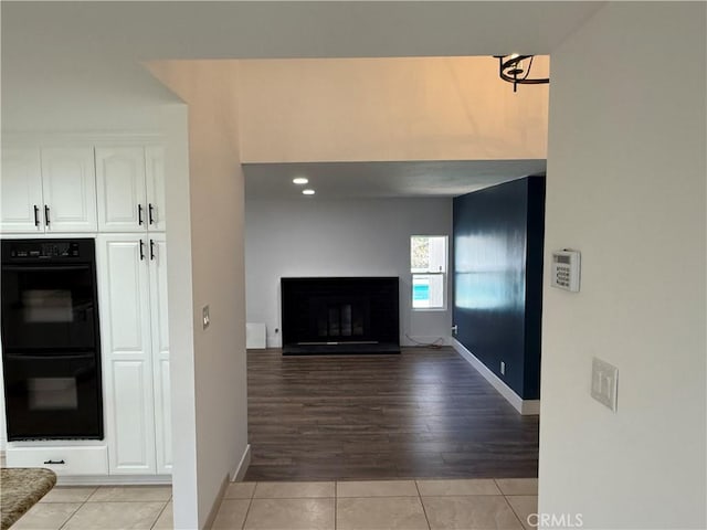 2440 Amelgado Dr, Hacienda Heights, CA 91745 - interior space featuring light tile patterned floors, a glass covered fireplace, dobule oven black, and white cabinetry