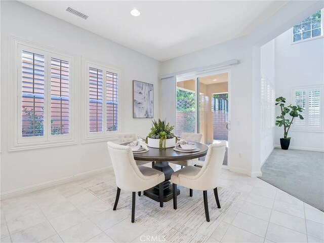 dining room featuring baseboards, visible vents, light tile patterned floors, and plenty of natural light