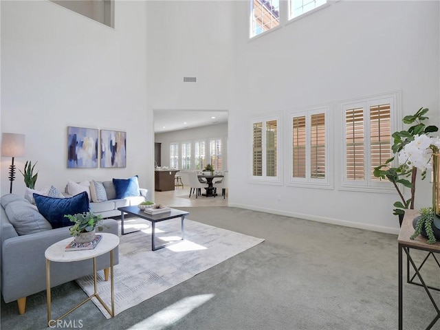 carpeted living area with baseboards and visible vents