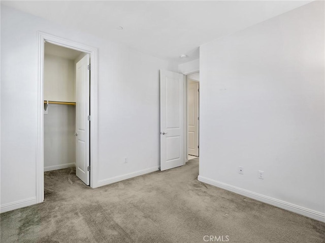 unfurnished bedroom featuring baseboards, a closet, a spacious closet, and carpet