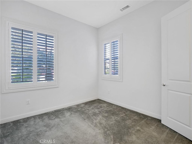 carpeted spare room featuring baseboards and visible vents