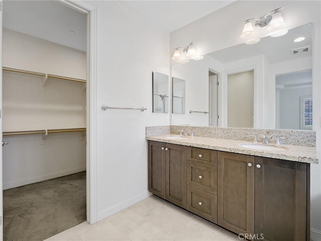 full bathroom featuring double vanity, a spacious closet, visible vents, and a sink