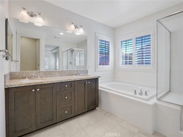 bathroom featuring a shower stall, double vanity, a sink, and a garden tub