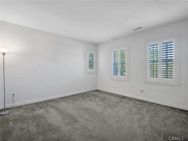 empty room featuring carpet floors, baseboards, and visible vents
