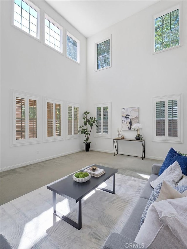 living room featuring a towering ceiling, carpet, and baseboards