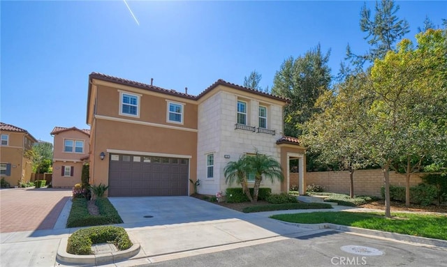 mediterranean / spanish-style house featuring a tile roof, concrete driveway, stucco siding, fence, and an attached garage