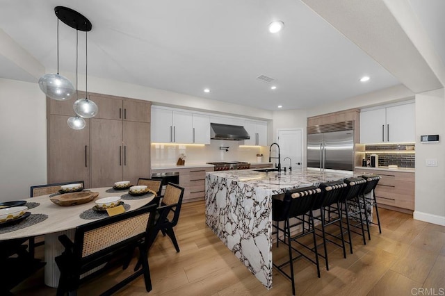 1452 Canoe Creek Way, Chula Vista, CA 91915 - kitchen featuring light wood finished floors, range hood, a sink, stainless steel built in fridge, and a breakfast bar area
