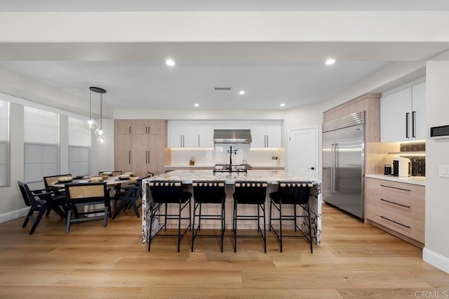 1452 Canoe Creek Way, Chula Vista, CA 91915 - kitchen with ventilation hood, visible vents, light wood-style floors, a kitchen bar, and built in fridge