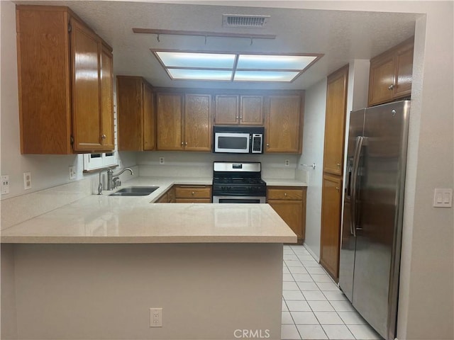 kitchen featuring visible vents, a sink, appliances with stainless steel finishes, a peninsula, and light countertops