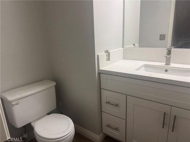 half bath with toilet, vanity, and baseboards