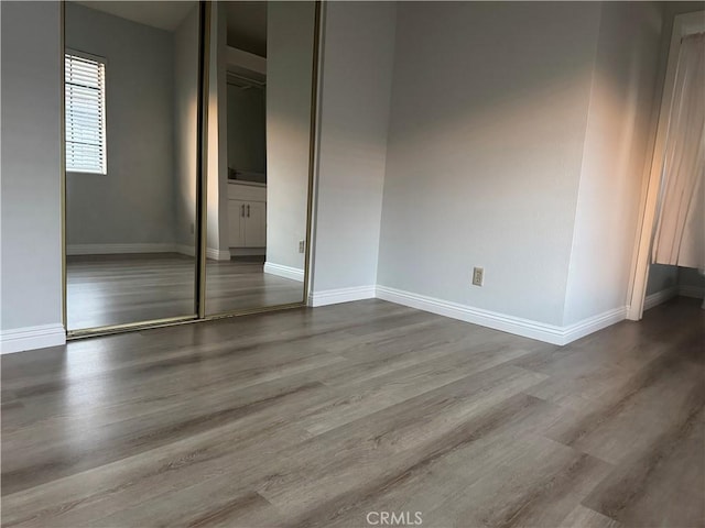 unfurnished bedroom with a closet, baseboards, and wood finished floors